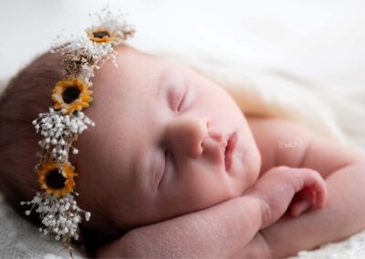bébé endormi tout en blanc avec couronne de fleurs séchées lors d'une séance photo naissance paisible et respectueuse à Béthune.